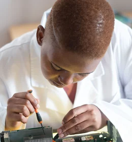Black electronics technician testing a circuit board