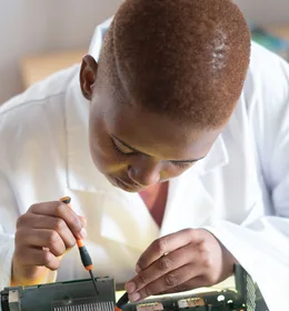Black electronics technician testing a circuit board