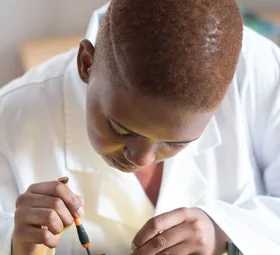 Black electronics technician testing a circuit board
