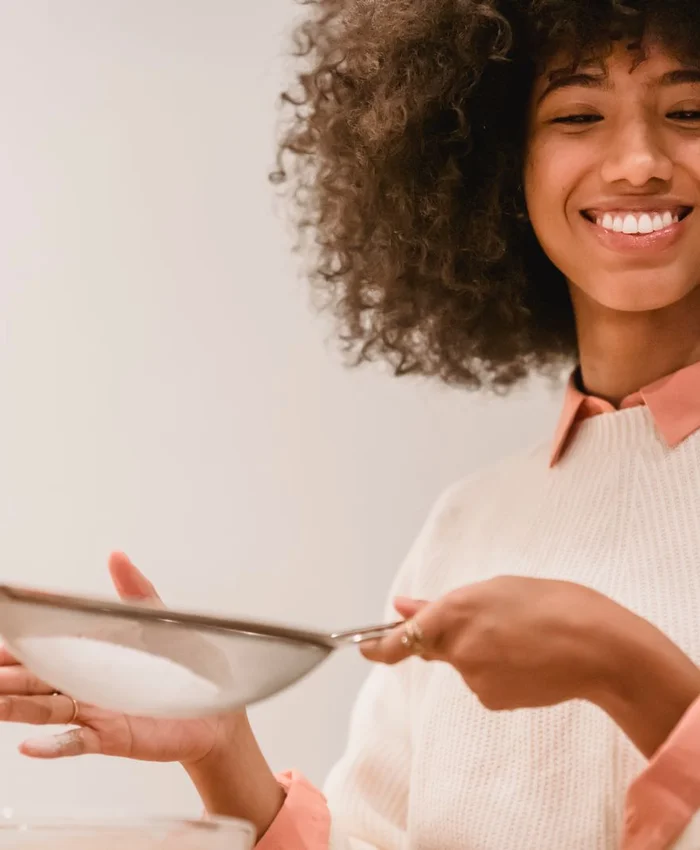 Black woman sifting flour in a kitchen