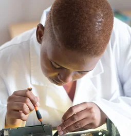 Black electronics technician testing a circuit board