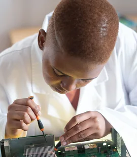 Black electronics technician testing a circuit board