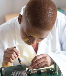 Black electronics technician testing a circuit board