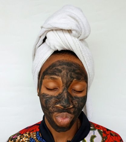 Black woman applying a clay skincare mask