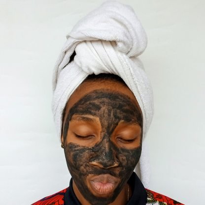 Black woman applying a clay skincare mask