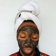 Black woman applying a clay skincare mask