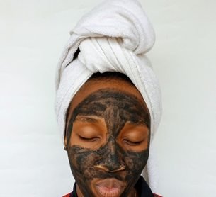 Black woman applying a clay skincare mask