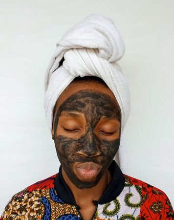 Black woman applying a clay skincare mask