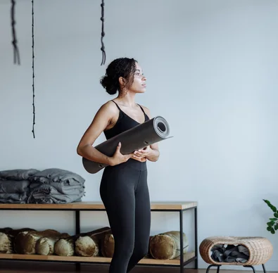 Black woman holding a yoga mat in a studio