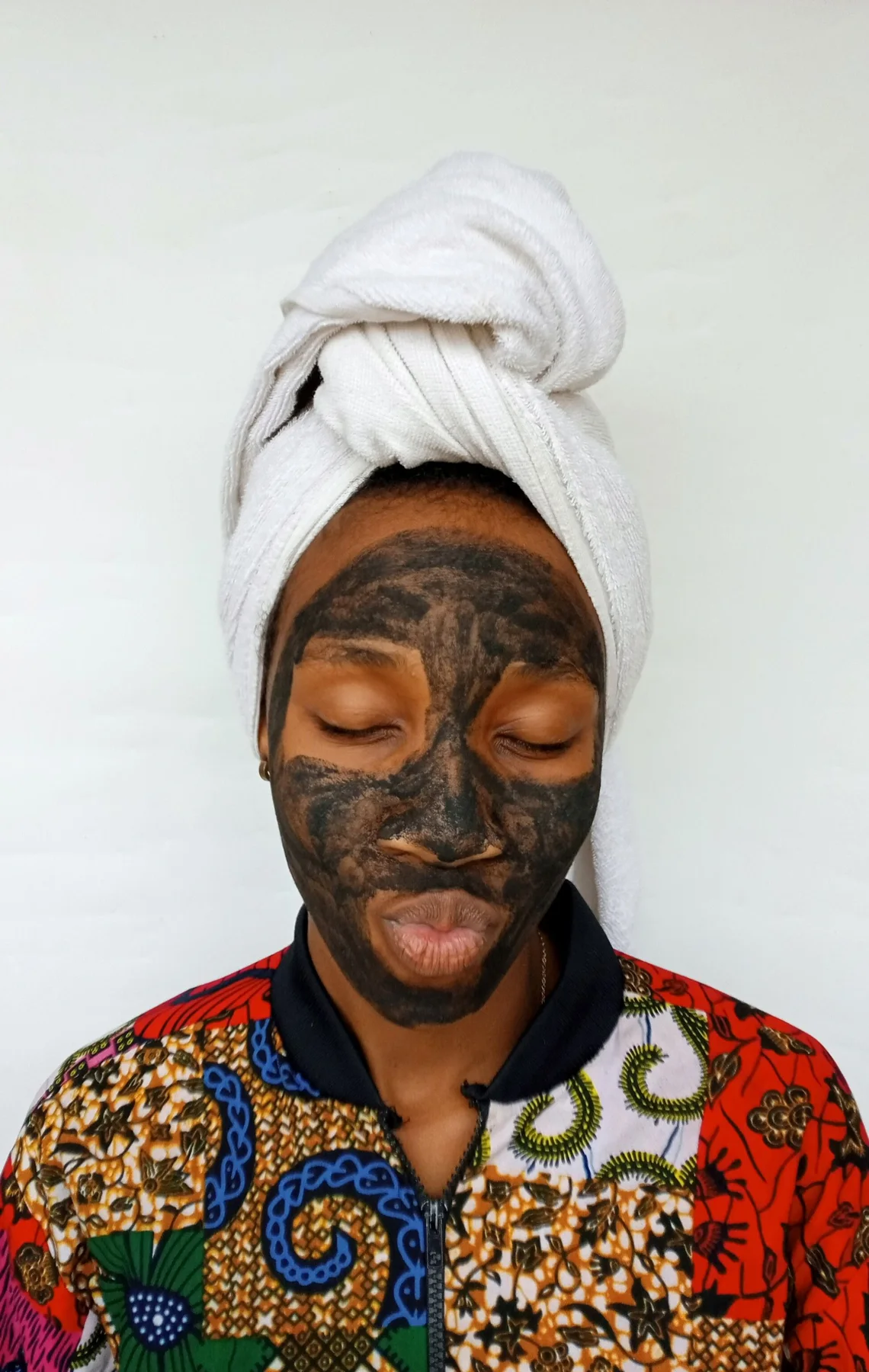 Black woman applying a clay skincare mask