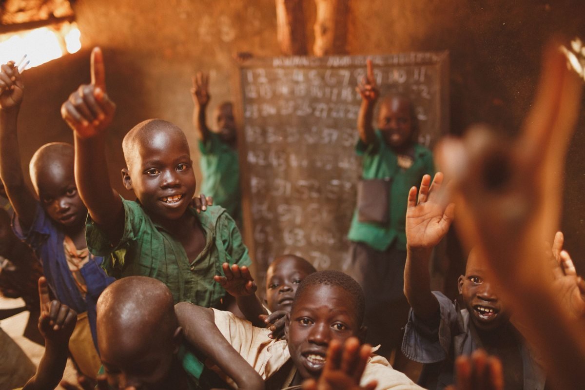 Pupils raising their hands in a Kitgum classroom