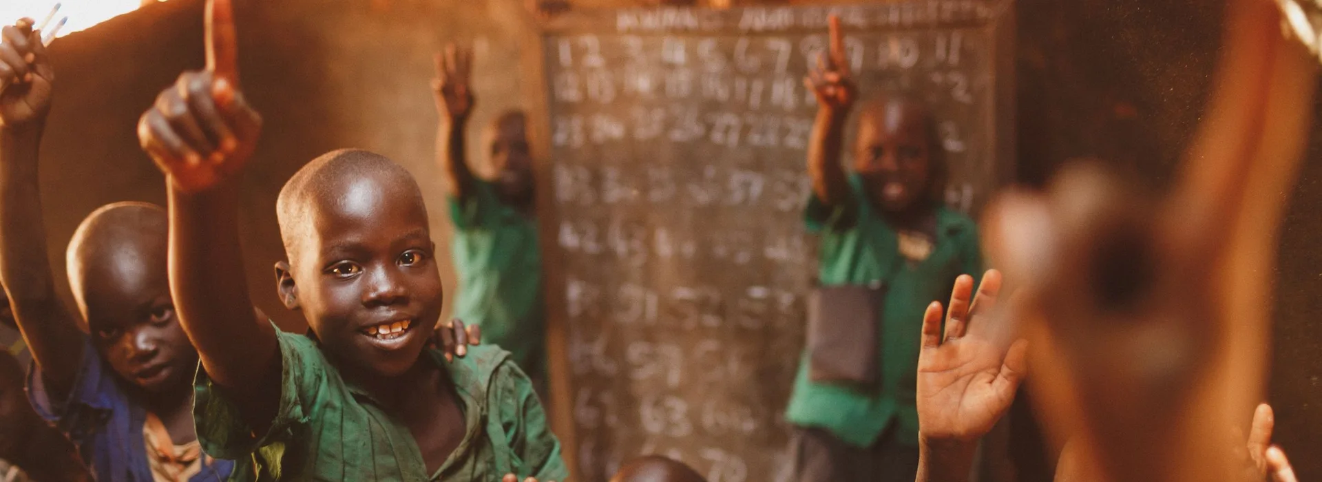 Pupils raising their hands in a Kitgum classroom