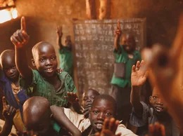 Pupils raising their hands in a Kitgum classroom