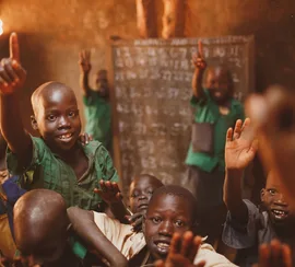 Pupils raising their hands in a Kitgum classroom