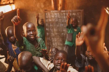 Pupils raising their hands in a Kitgum classroom