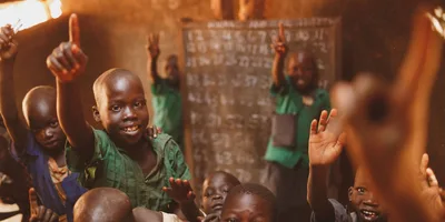 Pupils raising their hands in a Kitgum classroom
