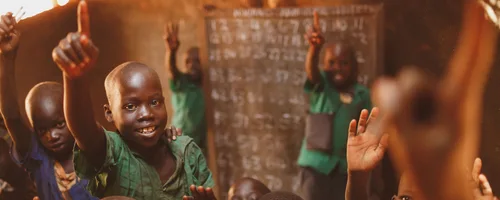 Pupils raising their hands in a Kitgum classroom