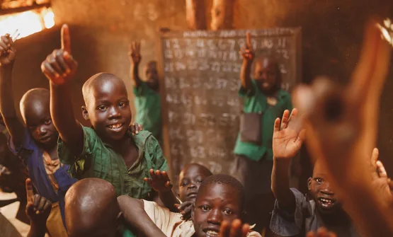 Pupils raising their hands in a Kitgum classroom