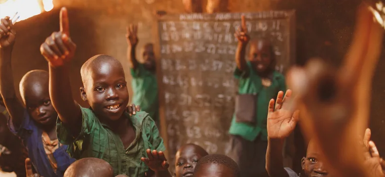 Pupils raising their hands in a Kitgum classroom