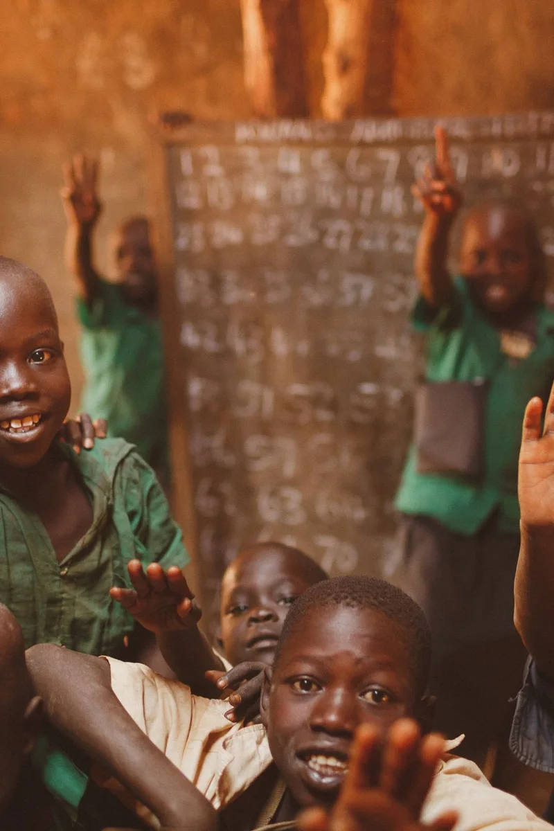 Pupils raising their hands in a Kitgum classroom